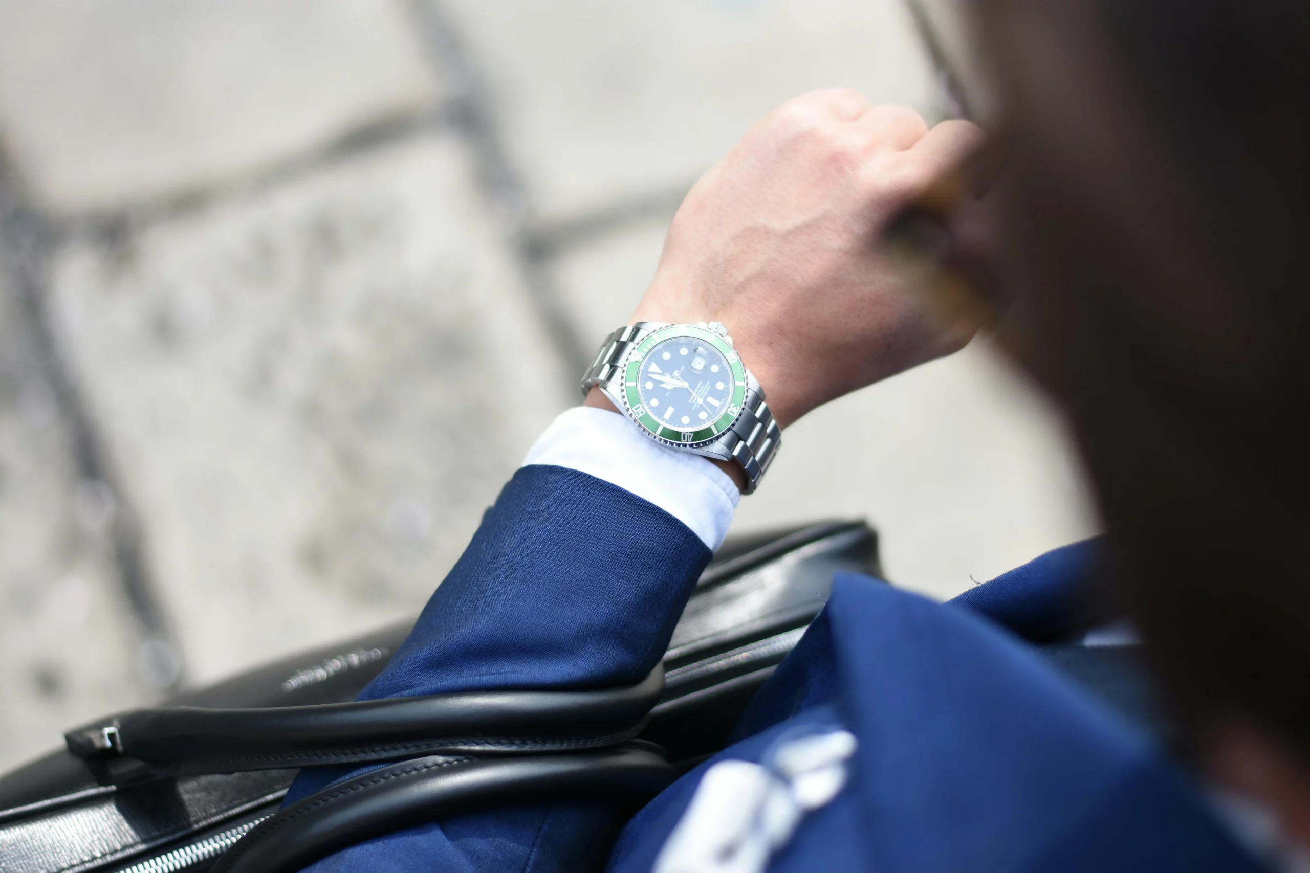 Ein Mann in einem eleganten blauen Anzug, der auf seine stilvolle Alltagsuhr schaut, symbolisiert Zeitmanagement und modernes Design.