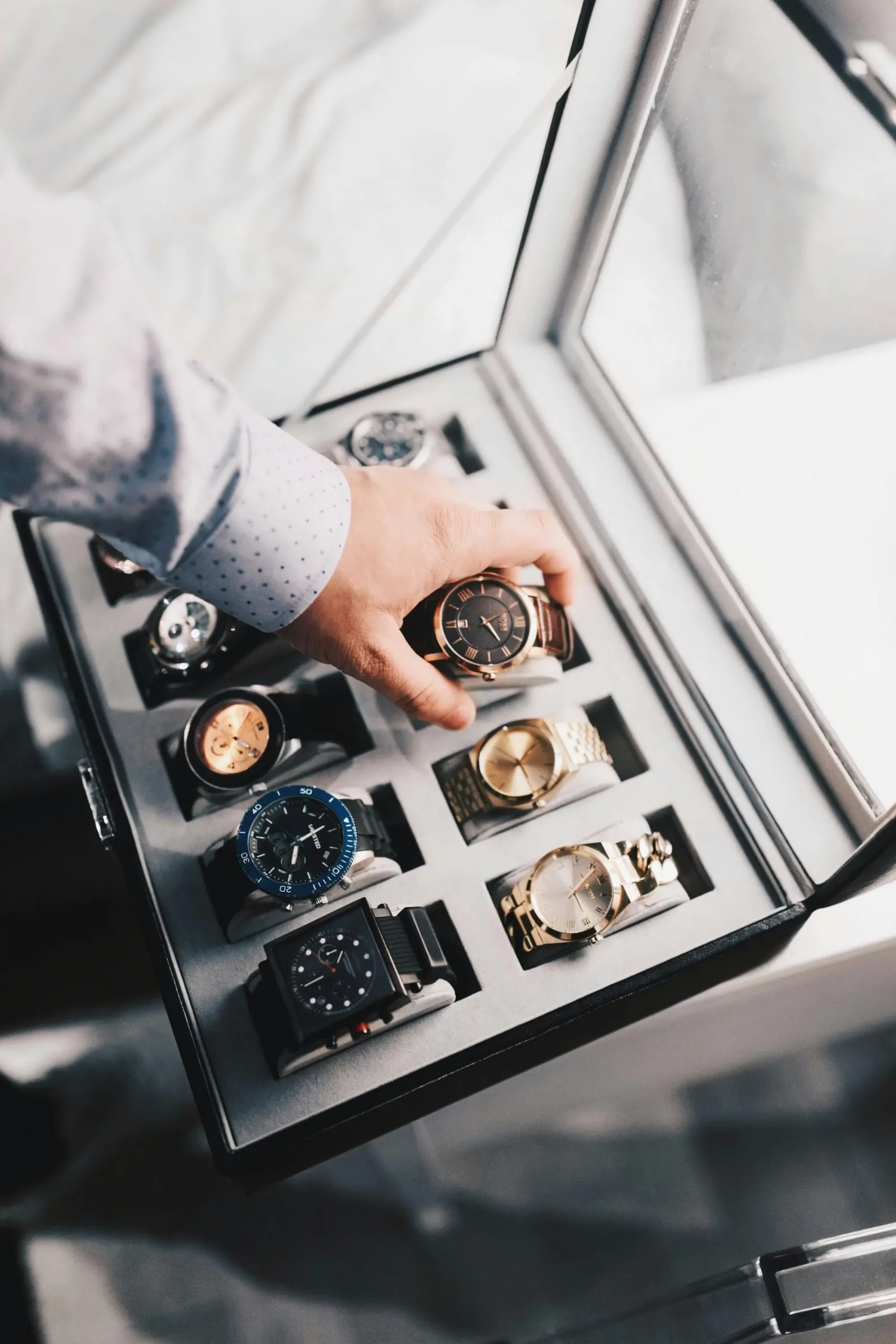 Eine männliche Hand, die eine luxuriöse Uhr aus einer edlen Aufbewahrungsbox entnimmt, präsentiert eine exklusive Luxusuhren-Kollektion.