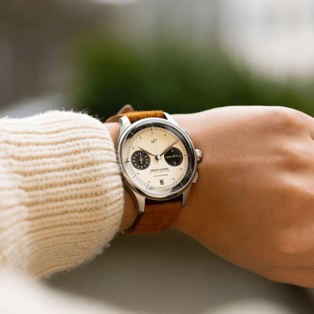 About Vintage 1934 Telechron am Handgelenk getragen, kombiniert mit einem eleganten Wildlederarmband.