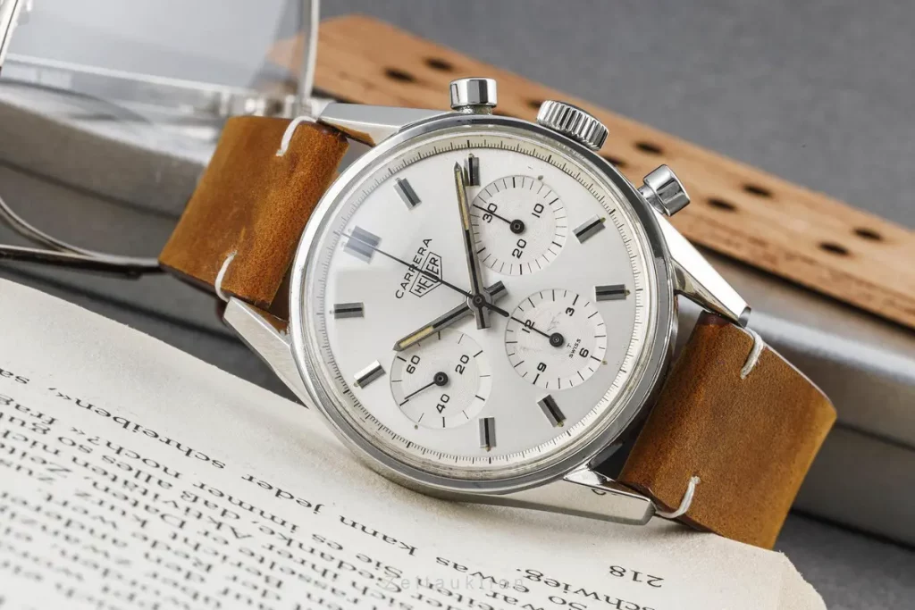 Die Heuer Carrera Ref. 2447 stilvoll auf einem Buch präsentiert, ein Symbol für Eleganz und Geschichte.