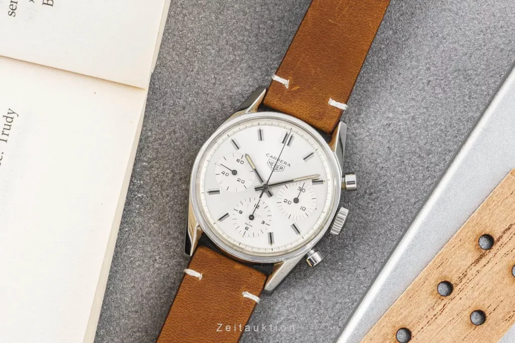 Die Heuer Carrera Ref. 2447 liegt flach auf einem Tisch, kombiniert mit ihrem klassischen Lederarmband.