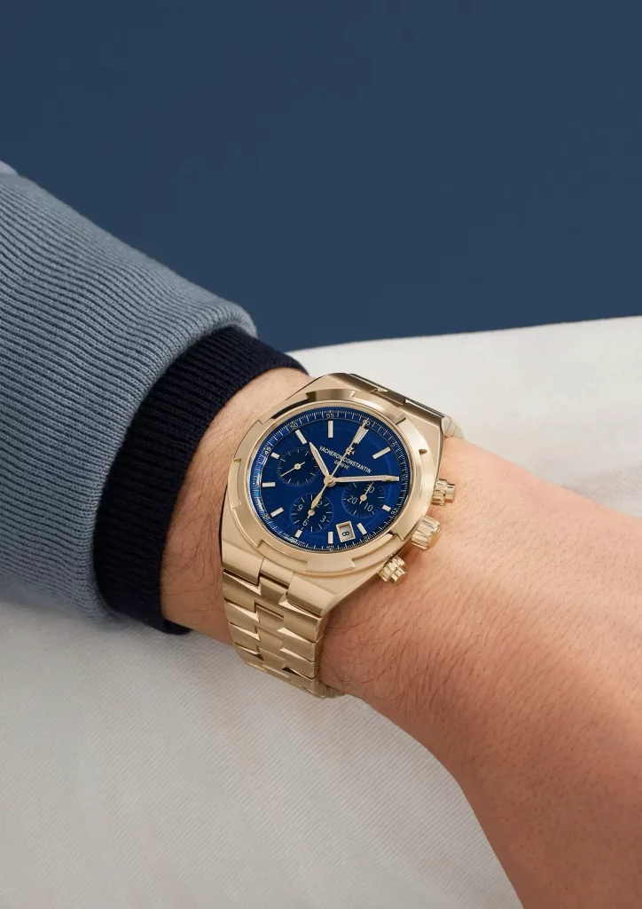 Goldene Vacheron Constantin Overseas mit blauem Zifferblatt, elegant am Handgelenk getragen.