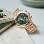 Goldene Vacheron Constantin Overseas mit grünem Zifferblatt, stilvoll auf einem Tisch arrangiert.